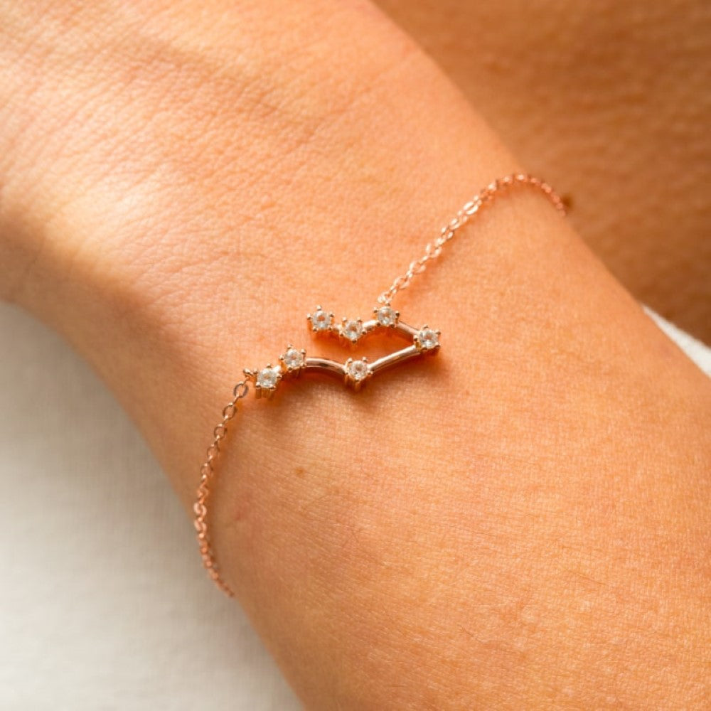 Een close-up van een verfijnde roségouden AstroChic Sterrenarmband, met fonkelende kristallen in de vorm van een sterrenbeeld. De minimalistische en elegante armband straalt persoonlijkheid en stijl uit, perfect als verstelbaar en uniek sieraad voor liefhebbers van astrologie en tijdloze schoonheid.