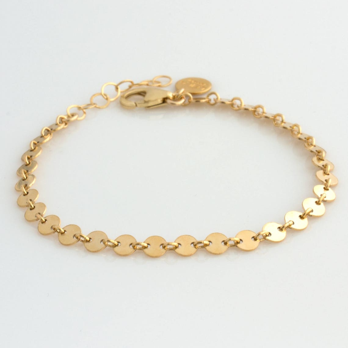 Een verfijnde gouden armband uit de Aurora & Blossom collectie, met een coin chain ontwerp dat subtiel glinstert. Deze elegante en persoonlijke armband straalt tijdloze klasse uit en is perfect om elke outfit te verrijken met een vleugje verfijning.