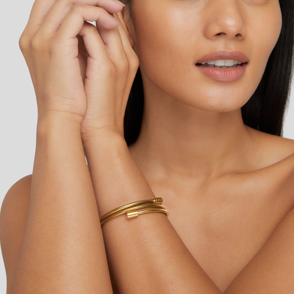 Vrouw draagt het Aurora Luxe armband – gedraaid en stijlvol ontwerp in goudkleur. Een elegant en modern accessoire, ideaal om een luxueuze en verfijnde touch aan elke outfit toe te voegen.