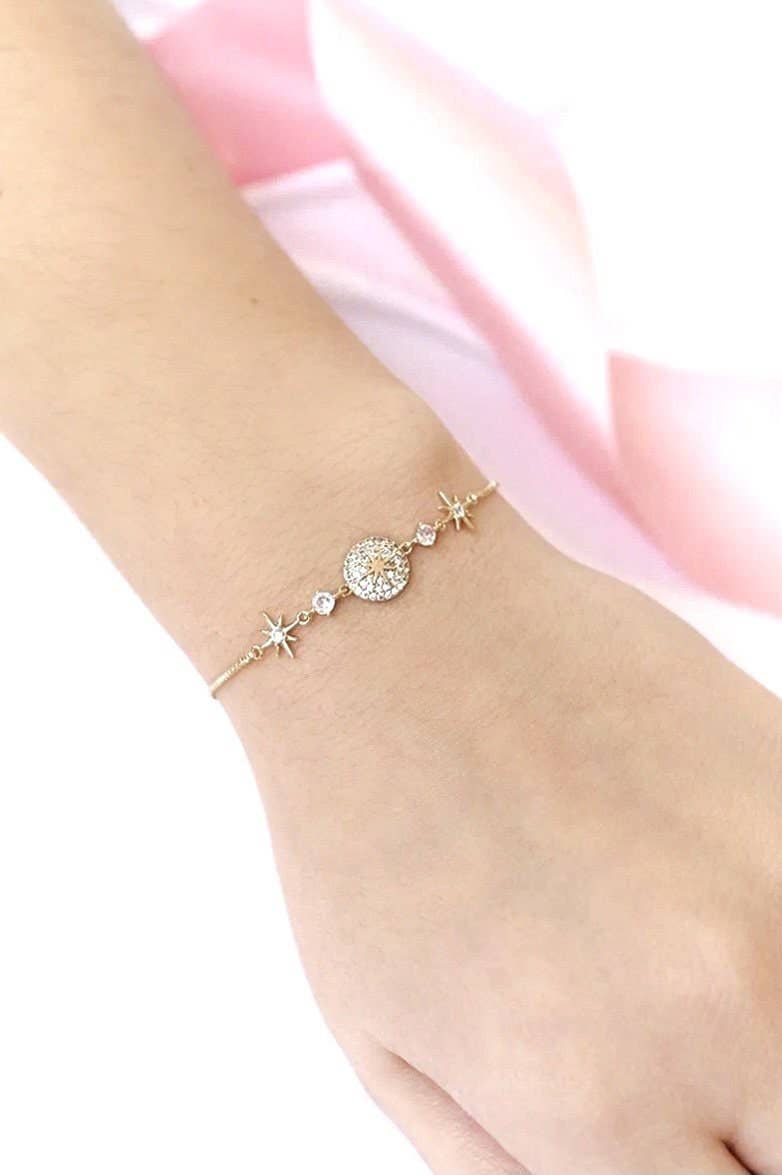 Close-up van de CharméLuxe armband, een gepersonaliseerde gouden armband met sprankelende details en sterren. Geeft een elegante en unieke uitstraling aan elke outfit.