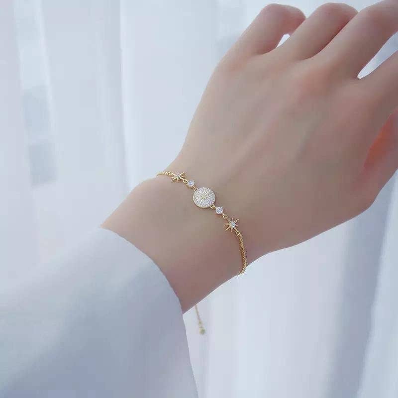 Hand met de CharméLuxe armband, een gepersonaliseerde gouden armband met delicate sterren en strass details. Perfect voor een elegante en unieke uitstraling.