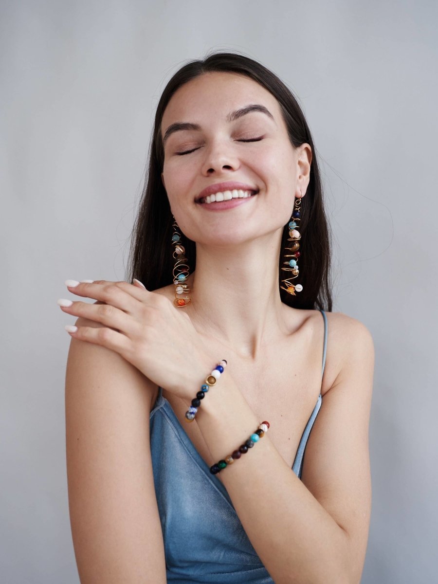 Vrouw met een stralende glimlach die de CosmoLuxe Solar System armband draagt, een kleurrijke en inspirerende accessoire met kralen die planeten voorstellen, perfect voor een mystieke look