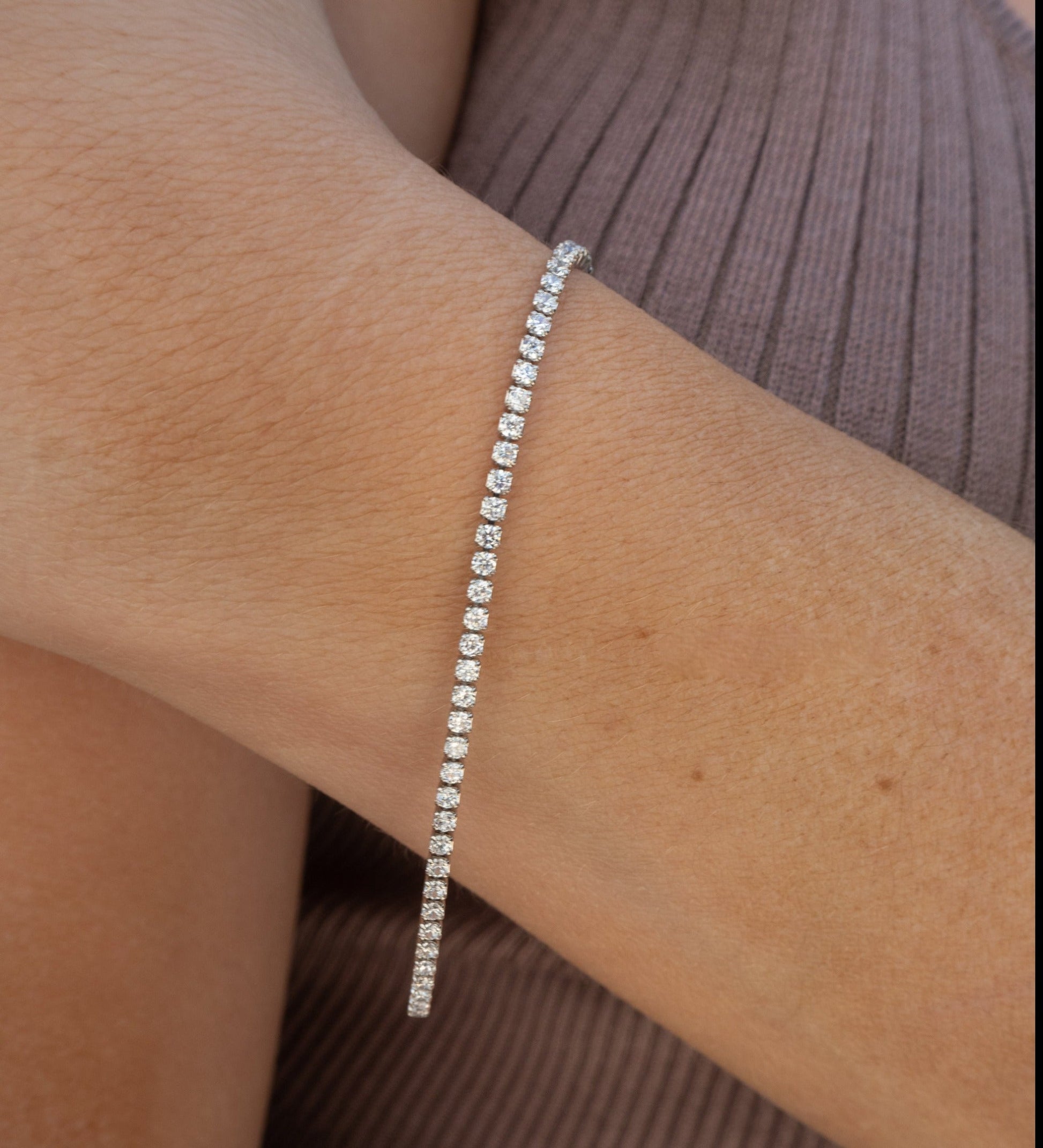 Een elegante tennisarmband van Eternal Charm met fonkelende stenen, gepresenteerd om de pols voor tijdloze schoonheid en verfijning.