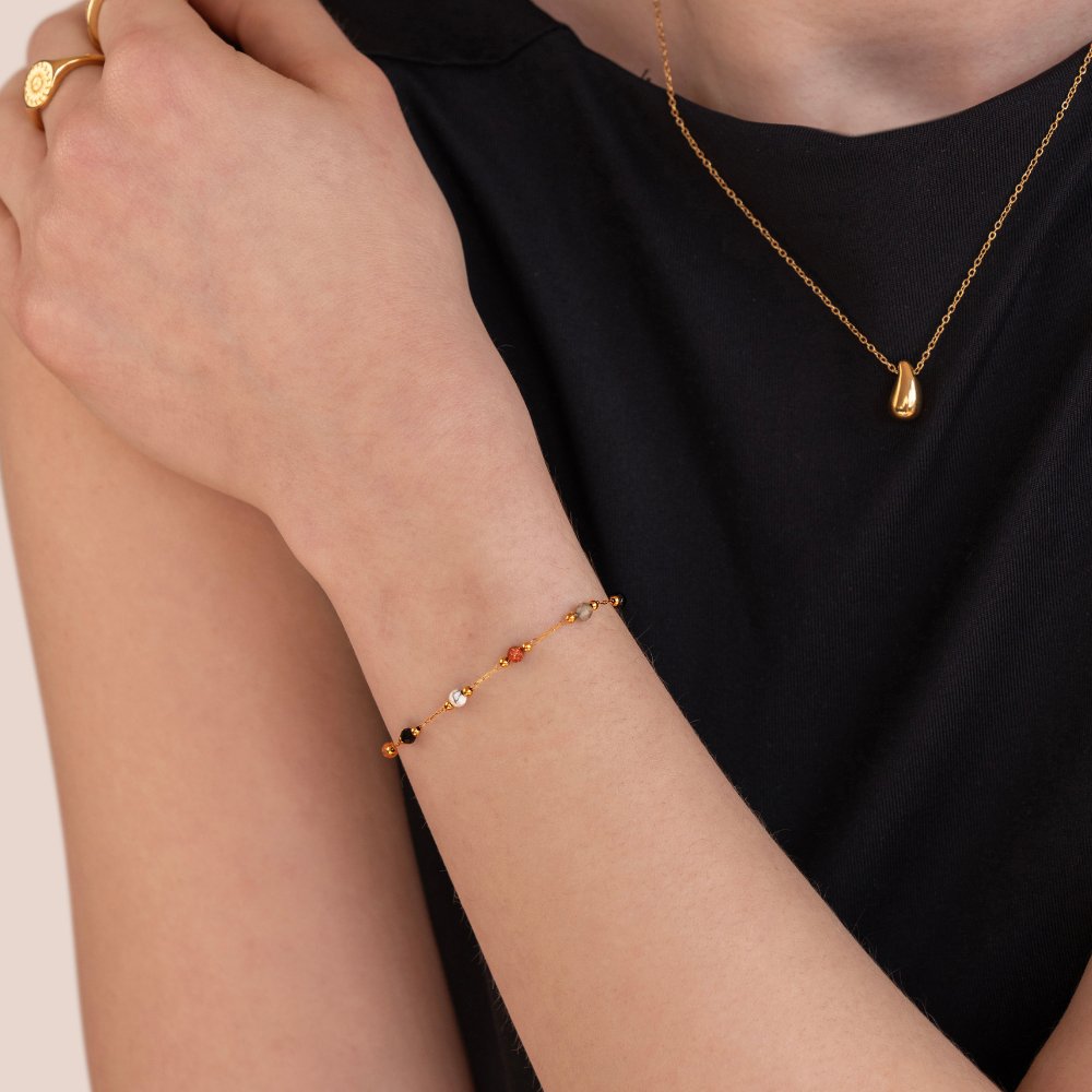 Vrouw draagt het GlowCharm Creations armband – elegant en kleurrijk design met fijne gouden schakels en subtiele kleurrijke kralen. Een perfect accessoire voor een stijlvolle en speelse toevoeging aan elke outfit