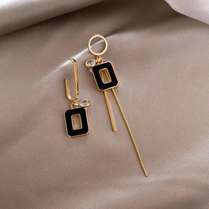 Liva oorhangers in goudkleur met zwarte rechthoekige details en subtiele glinsterende stenen. De asymmetrische vorm geeft een speelse en elegante uitstraling. De lange hanger met een fijne gouden ketting voegt een verfijnde touch toe, terwijl de kortere oorbel zorgt voor balans. Ideaal voor een moderne, chique look.