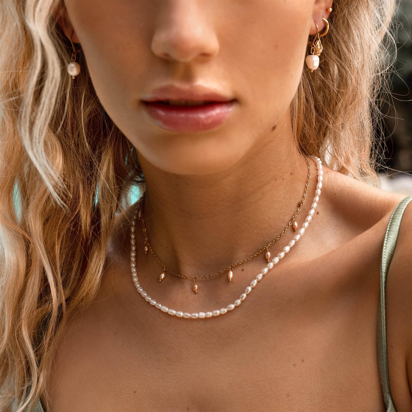 Afbeelding van de Lora Lux  Ketting Verfijnd, een delicate parelketting met subtiele gouden accenten, gedragen door een model. Het ontwerp is verfijnd en elegant, perfect voor een chique look. De ketting combineert stijlvol met andere sieraden, wat het een veelzijdig accessoire maakt.