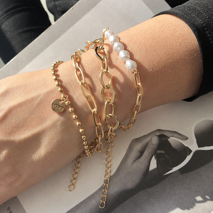 Een stijlvolle pols met het Lumineux Flair kralenarmbandje in goud en parels, een symbool van subtiele luxe en verfijning