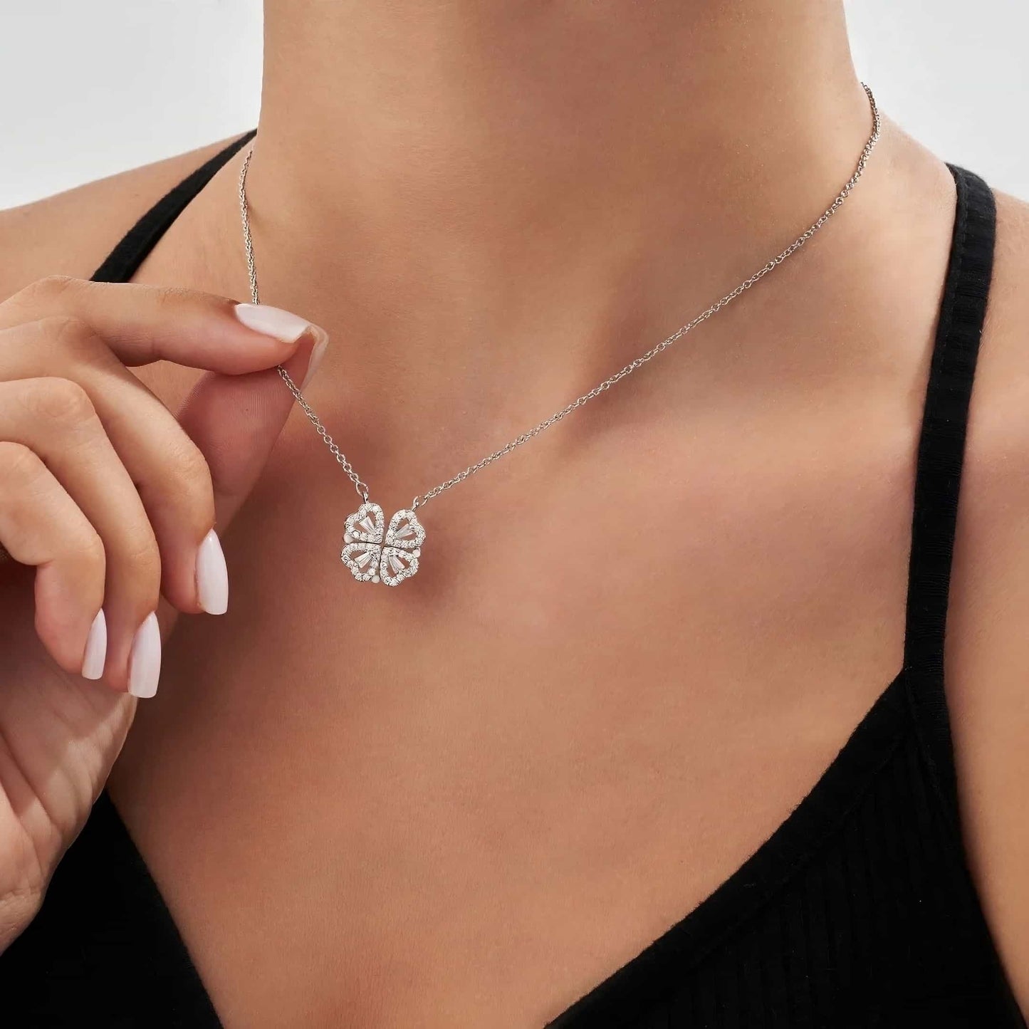 Een elegante vrouw draagt de Luminous Charm zilveren hartketting met een verfijnd bloemvormig hangertje. De schitterende details van de Luminous Charm ketting benadrukken de tijdloze en elegante uitstraling, ideaal voor elke gelegenheid.