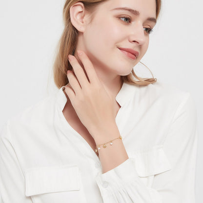 De Lustrous Joy armband is een charmant en stijlvol verfijnd accessoire, gedragen door een vrouw die de elegante uitstraling van de gouden ketting met delicate parel- en schelpendetails benadrukt. Het sierlijke ontwerp straalt subtiele luxe uit en is perfect voor een verfijnde look op elke gelegenheid. De armband combineert maritieme elementen met een moderne flair voor een tijdloze charme.