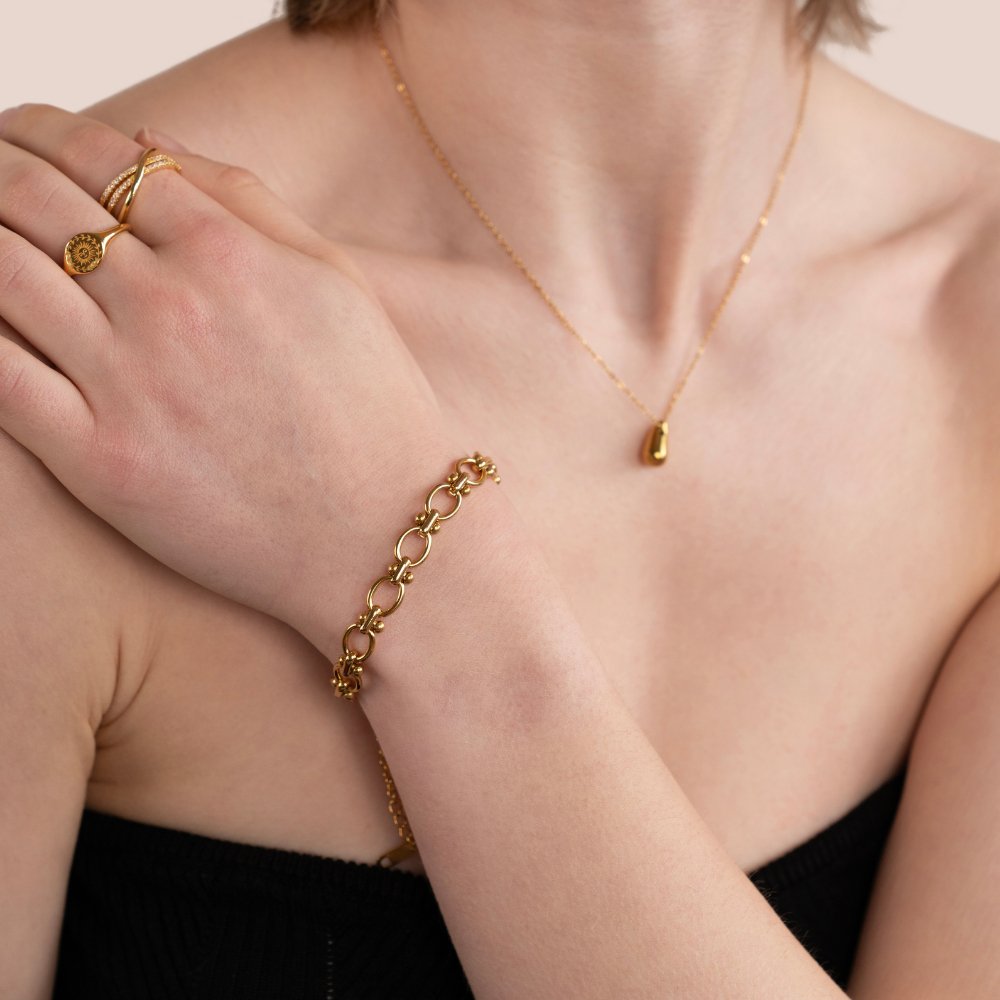 Elegante gouden armband van LuxeGlow, gecombineerd met een bijpassende ketting en ring. Tijdloos en stijlvol design, perfect voor een verfijnde look.