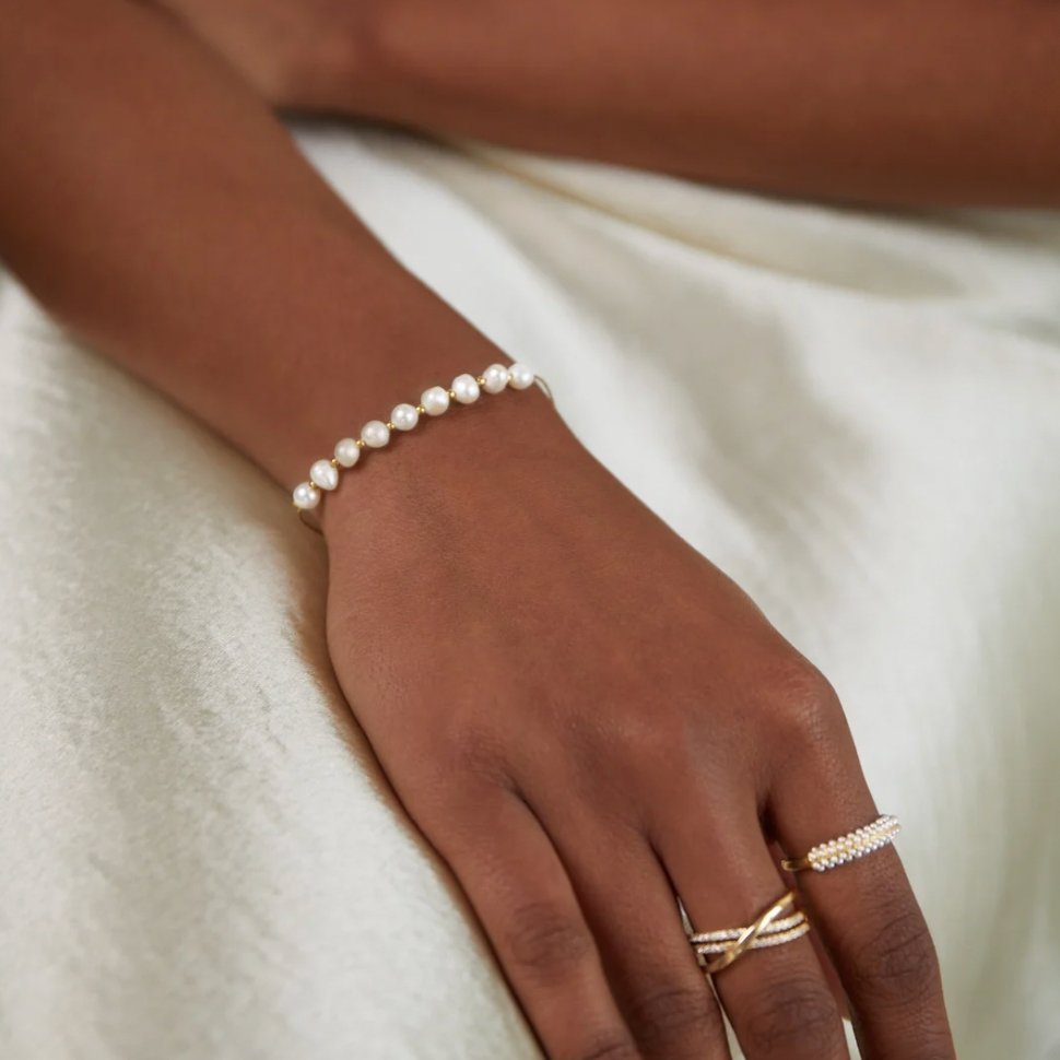 Hand met het PureLuxe Jewelry armband – tijdloos en verfijnd parelontwerp. Stijlvol accessoire dat elke outfit voorziet van een klassieke, elegante uitstraling. Ideaal voor formele en feestelijke gelegenheden