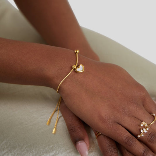 De SoulEmbrace armband heeft een liefdesvol ontwerp met een delicate gouden ketting en een charmante hartvormige hanger. Het is een elegant sieraad, perfect voor elke gelegenheid, dat zowel subtiel als verfijnd is. Het verstelbare ontwerp maakt het een veelzijdige keuze voor elke pols.