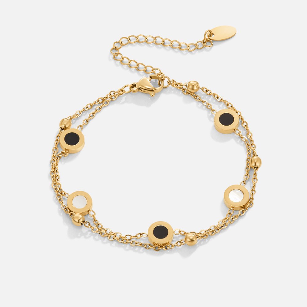 UniekAura armband – elegant gouden ontwerp met dubbele ketting en verfijnde ronde details in zwart en parelmoer. Een stijlvol accessoire dat elke outfit voorziet van een unieke en chique uitstraling